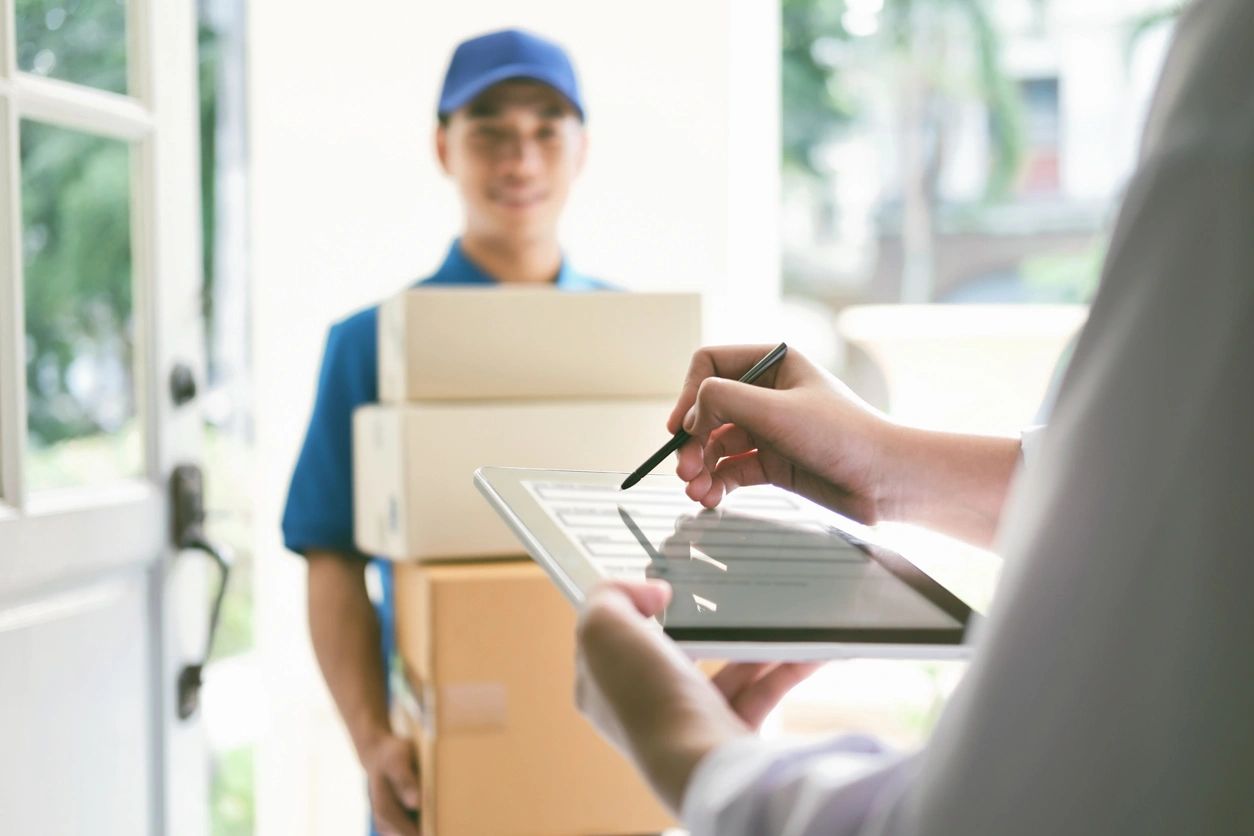 Delivery person with packages and digital signature.