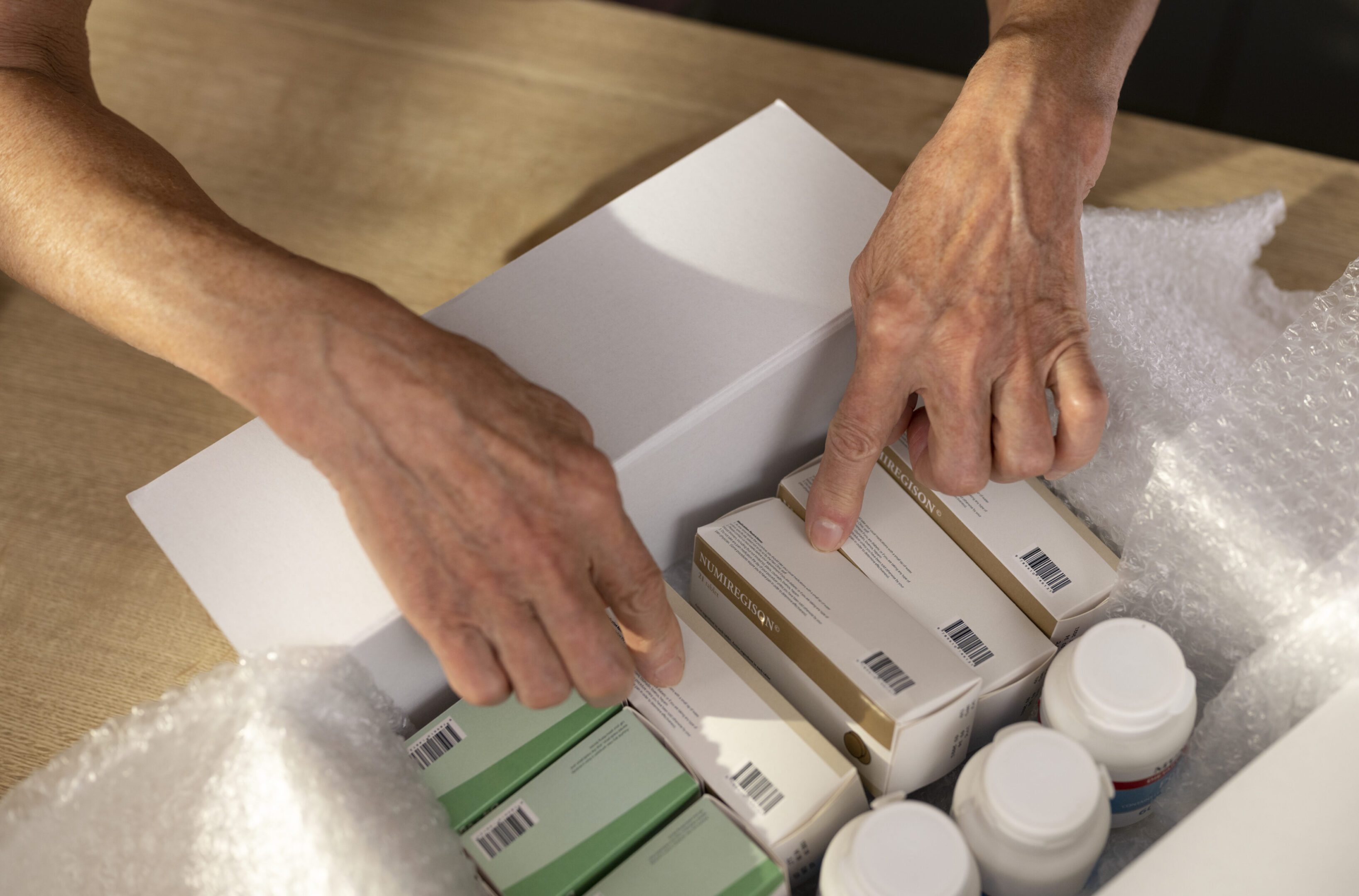 Close-up of hands holding medicine in box.